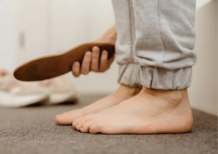 Persoon op blote voeten met een schoenzool in de hand